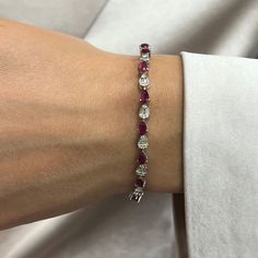 This Beautifully Crafted Tennis Bracelet Features Pear Shaped Rubies With Baguette And Round Cut Diamonds In Prong And Channel Setting. Crafted In 14k White Gold. Total Diamond Weight: 1.58 Carats. Diamond Quality: G-H Color And Si Clarity. Total Ruby Weight: 4.68 Carats. Length: 7 Inches. Width: 3.8mm. Total Weight: 9.38 Grams. Bracelet Closes Securely With A Box Clasp. This Tennis Bracelet Is A Timeless Piece That Holds A Place In The Collection Of Every Jewelry Lover. Comes With A Presentable Ruby And Diamond Bracelet, Ruby Tennis Bracelet, Elegant Ruby Tennis Bracelet For Formal Occasions, Fine Jewelry Red Diamond Bracelet For Formal Occasions, Elegant Red Tennis Bracelet For Anniversary, Elegant Red Tennis Bracelet, Formal Red Diamond Jubilee Bracelet, Red Tennis Bracelet With 17 Jewels For Wedding, Elegant Red Diamond Bracelet For Formal Occasions