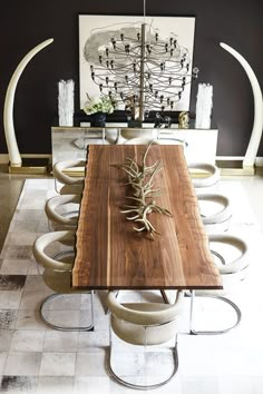 a dining room table with chairs and a plant on top of it in front of a mirror