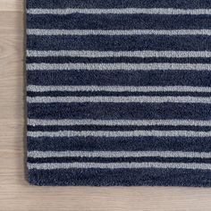 a blue rug with white and gray stripes on it, sitting on a wooden floor