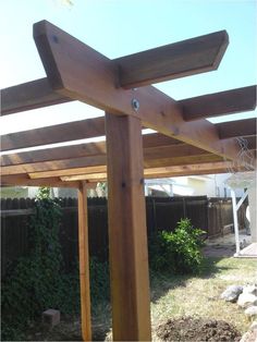 a wooden pergola in the middle of a yard