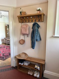 a coat rack with shoes and purses hanging on it next to a wooden bench