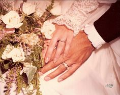 the bride and groom are holding hands with their wedding rings on top of each other