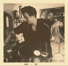 a man standing in front of a counter top next to a bottle and glass container