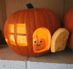 a pumpkin carved to look like a house with a window and smiling face in it