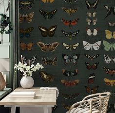 a wall covered in lots of butterflies next to a table with flowers and vases on it