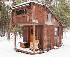 a small wooden cabin in the woods with snow on the ground