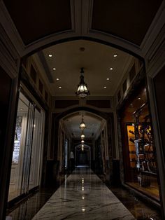 an empty hallway in a building with chandelier hanging from the ceiling and marble floors