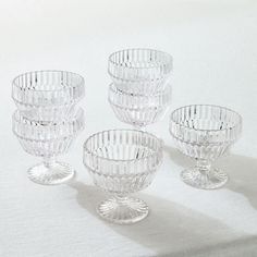 four clear glass bowls sitting on top of a white table