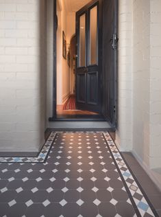 an open door leading to a hallway with black and white tiles