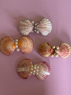 three seashells with pearls on them sitting on a pink surface