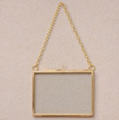 a gold frame hanging from a chain on a wall