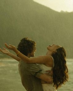 a man and woman hugging on the beach in the rain