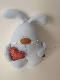 a blue stuffed animal with a heart hanging from it's side on a wall