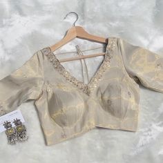 Elevate your traditional wardrobe with this stunning light beige golden sequin blouse, designed for elegance and comfort. Crafted from luxurious sequin fabric, this blouse features a stylish V-neck on both the front and back, perfect for adding a touch of sophistication to your ensemble. The back thread detailing adds a unique flair, while the lace trim around the neckline enhances its delicate beauty. Ideal for pairing with sarees or lehengas, this versatile piece will make you stand out at wed Cheap Gold Blouse With Cutdana, V-neck Blouse Piece For Diwali Reception, Festive V-neck Choli With Mirror Work, Elegant V-neck Blouse For Festive Occasions, Elegant Festive V-neck Blouse, Elegant V-neck Choli With Resham Embroidery, Elegant V-neck Sets With Padded Blouse, Elegant Beige Saree With Unstitched Blouse, Elegant Gold Blouse Piece With Mirror Work