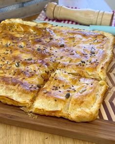 a wooden cutting board topped with four square pieces of bread covered in seeds and seasoning