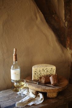 a bottle of wine sitting next to a piece of cheese on top of a wooden table