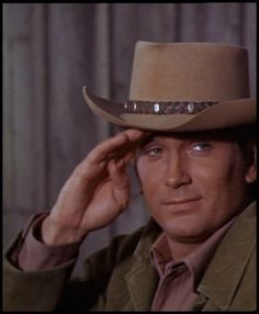 a man in a cowboy hat is posing for a photo with his hand on his head