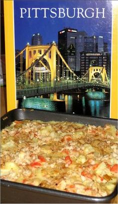 a pizza sitting on top of a pan in front of a book titled pittsburgh