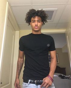 a young man with curly hair standing in a hallway