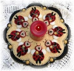 a candle holder with ladybugs on it and a red candle in the middle