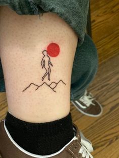 a person with a small tattoo on their leg that has a red dot in the middle