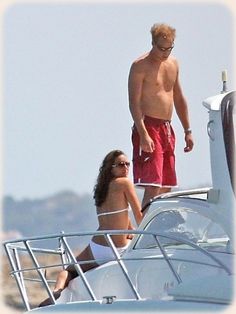 a man and woman on a boat in the water with another person standing next to them