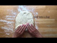 a person is kneading dough on top of a wooden table with the words roll into a log