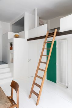 a ladder leaning against the wall next to a table and chair in a room with white walls