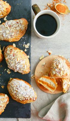 several pastries on a table next to a cup of coffee and an orange peel