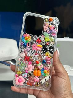 a person holding up a phone case with lots of stickers on it