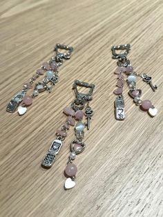 three necklaces are laying on a wooden table together, with charms attached to them