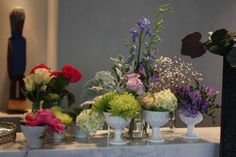 several vases filled with different types of flowers on top of a white marble table