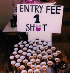 a table topped with lots of cups and a sign that says entry fee 1 shot