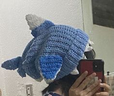 a person taking a selfie in front of a mirror wearing a crocheted elephant hat