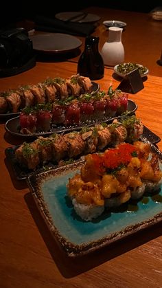 sushi platters are arranged on a wooden table