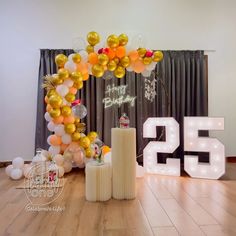 a large balloon arch with the number twenty five in front of it and balloons on the floor