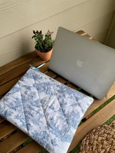 an open laptop computer sitting on top of a wooden table next to a potted plant