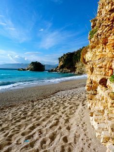 a sandy beach next to the ocean under a blue sky