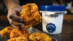 a person is holding some fried food in their hand and dipping it into a bowl