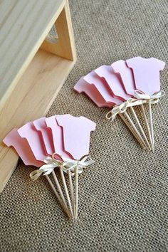 pink paper flowers are placed on the floor next to a piece of wood and string