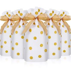 four white and gold polka dot wrapped gift bags with golden ribbon on each one side