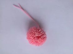 a pink pom - pom on a white surface with a string attached to it