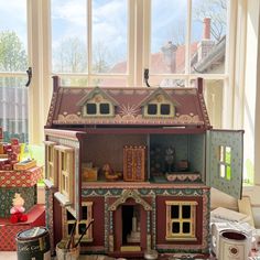 a doll house sitting on top of a table in front of a window next to boxes