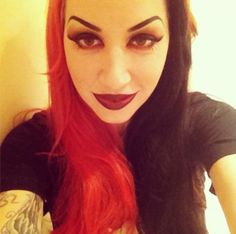 a woman with long red hair and black makeup