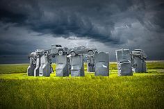 a group of stonehenge standing in the middle of a field under a stormy sky