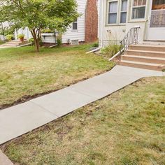 a sidewalk in front of a house with grass