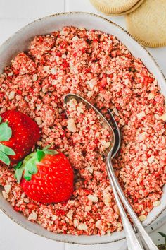 two strawberries in a bowl next to some cookies