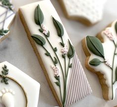 cookies decorated with white icing and green leaves on top of each other, sitting on a table