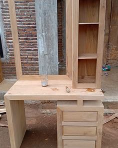 a wooden desk with shelves and drawers on it in front of a brick building that is being built