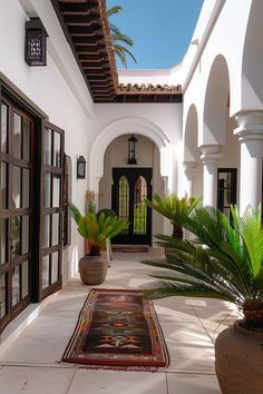 an outdoor courtyard with potted plants and rugs on the floor in front of it